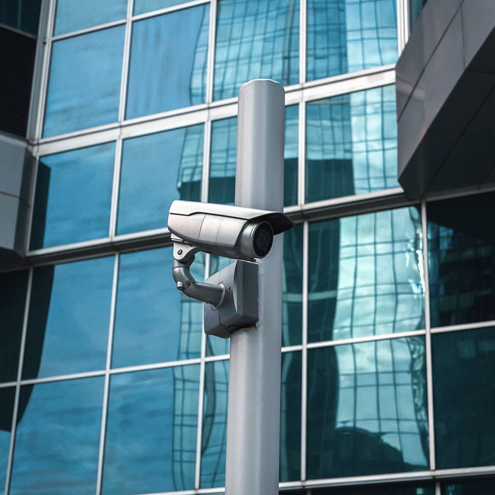 External surveillance camera against glass building facade